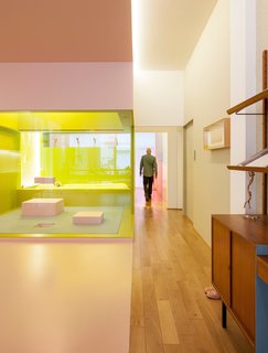 A Creative Dreamworld Complete With Neon Rooms and a Tropical Garden - Photo 3 of 11 - In the upstairs apartment, glass partitions keep the elongated loft open and spacious, while lighting is placed against brightly colored walls to create a cool, atmospheric glow.