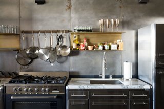 Floating brass shelves fabricated by local sculptor Gilad Ben-Artzi contrast the steel wall.
