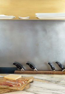 A plated burnished brass pot rack from Hayneedle hangs above the Verona range. Resting on the countertop is a knife block from Horne.