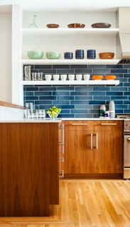 The residents have a particularly strong sense of color and love to cook with their son, so no-fuss finishes likes these blue tiles from Heath Ceramics were an ideal choice. The tiles combine with colorful tableware and custom walnut cabinetry to make a vibrant inteiror.