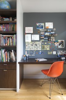 Upstairs, their son’s bedroom features a built-in walnut bookshelf and desk. Smart details—like the magnetic paint in lieu of a bulletin board—help keep the space tidy. The chair is an Eames Molded Fiberglass Side Chair.