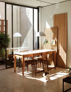 One-of-a-Kind Furniture Fills This Delightfully Serene Buenos Aires Home - Photo 3 of 10 - In the dining area, a one-of-a-kind table with a reclaimed Carrara marble top by NET—themultidisciplinary design firm of architect Alejandro Sticotti, with whom Nicolas works—is surrounded by prototypes of the company’s Board chair. The family dog, China, sits on a floor made of travertine tiles.