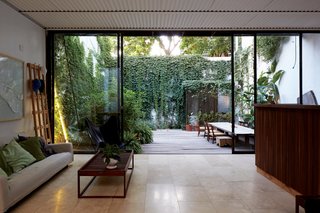 One-of-a-Kind Furniture Fills This Delightfully Serene Buenos Aires Home - Photo 4 of 10 - The main living area is flanked by green spaces, with custom sliding doors made from materials sourced from a metal warehouse. The ceiling is corrugated sheet metal, a "common and cheap but noble" construction material, Teresa says.