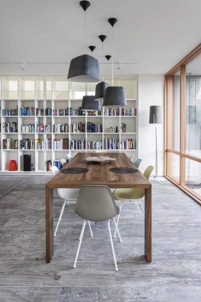 Bordering the dining room is an entry courtyard and a partially open bookcase wall, custom designed and fabricated in Dovetail’s own wood and metal shop. Daltile Season Wood porcelain tile offers tonal contrast with Ligne Roset Eaton dining table and Quantum wood window frames. Eames Molded Plastic chairs and Tom Dixon Felt pendant lights complete the space. Photo 3 of Central District Residence modern home