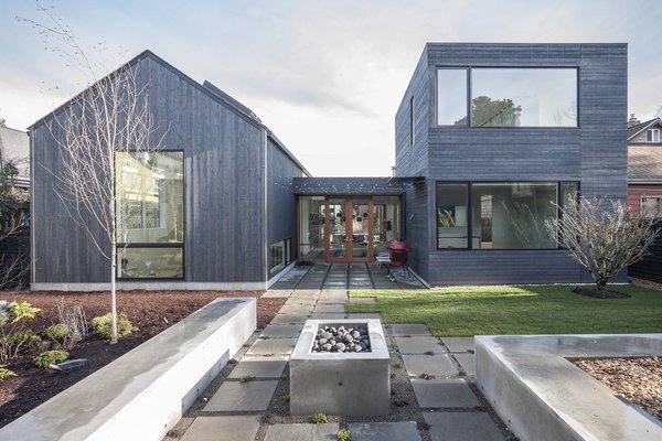 Modern home with outdoor, pavers patio, porch, deck, back yard, and grass. The two volumes converge at an exterior courtyard. On the gabled side, skylights bring light into the artist studio; on the cube side, a garden occupies the flat roof. The team used eco-friendly Wet-flash on the roof to draw away moisture from the outside, while allowing a permeable escape for water vapor from the inside. During the estimation and design phases, Dovetail worked closely with Heliotrope to cost engineer and rework elements in order to stay within the client’s budget. The metal roof of the original design was discarded in favor of a simpler and more economical black composite roof. Photo 10 of Central District Residence
