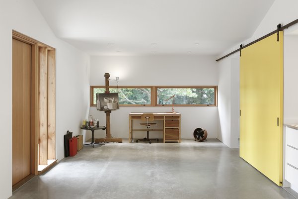 “Concrete floors, drywall, and minimal use of trim allowed for the feel of the space to remain utilitarian, while exposed Douglas fir structural members created a connection to regional Pacific Northwest design,” Schaer says. The clients wanted a place for painting and occasional freelance work, which fits opposite the room's fireplace and seating area. A Kevi Chair by Jørgen Rasmussen accompanies the desk. Photo 5 of Horse Stable Studio modern home