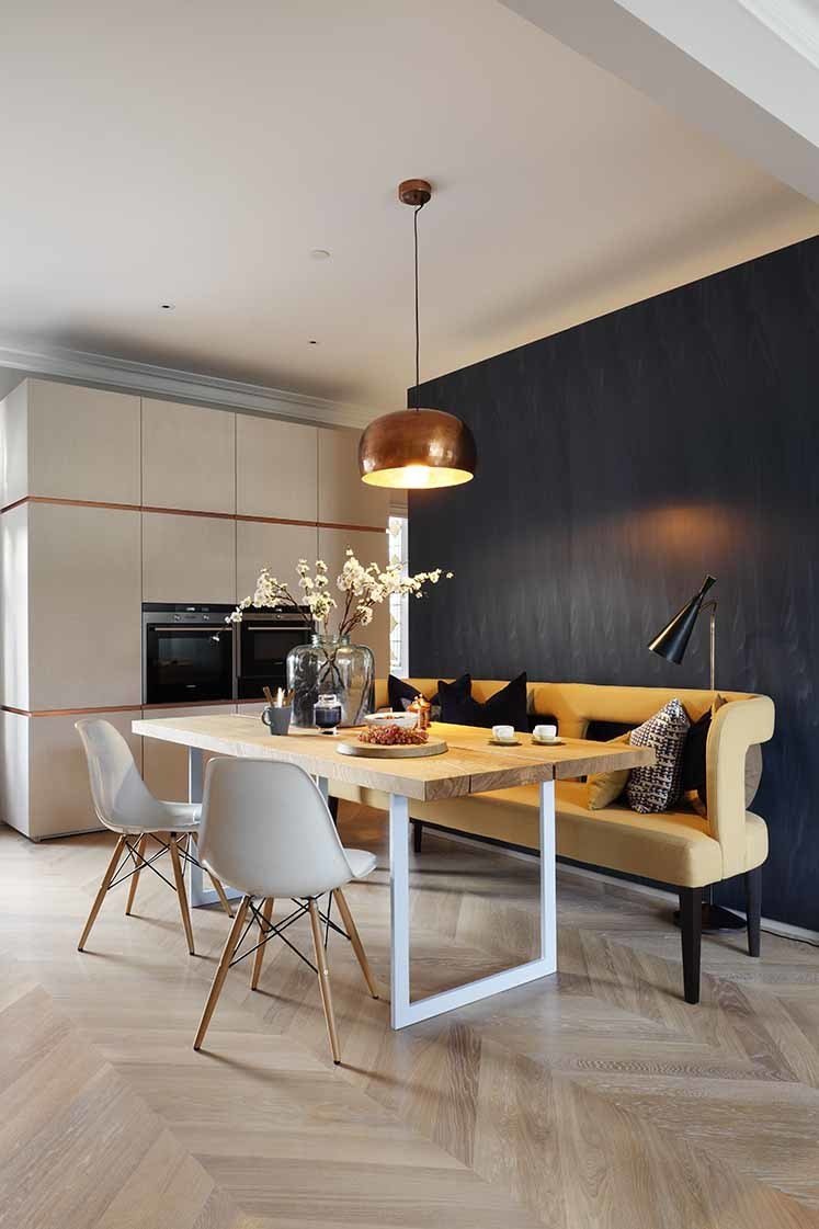 Adding wood floors to the home proved to be a challenge, both in terms of approval and execution. Since the flat is located in a historic mansion block, the license to alter it was very strict. Once approved, floating oak parquet floors were installed above a high-performance acoustic system to offer sound insulation for the neighbor below. The open dining room exemplifies the clients’ wish for a “fun yet minimalist” home. A copper Habitat pendant lamp hangs above a solid oak dining table fabricated by INTERIOR-iD. A whimsical mustard sofa pops against the blue Tabu veneer wall.