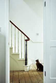 The hallway’s matte-white paint is a crisp backdrop to refurbished details like the balustrade.