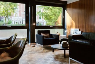 We Can't Get Enough of This German Apartment's Sleek Matte-Black Kitchen - Photo 4 of 11 - The home is a showcase for the modern furnishings the residents have collected over the years. Vintage armchairs by Florence Knoll and a PA05 Leila coffee table from e15 outfit the living room.