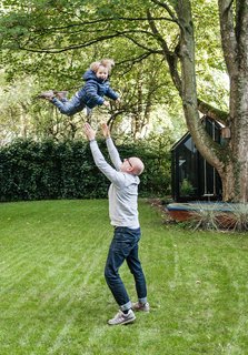 We Can't Get Enough of This German Apartment's Sleek Matte-Black Kitchen - Photo 6 of 11 - Fabian plays with Morten in the yard, which features a spacious lawn and a greenhouse.