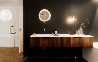 We Can't Get Enough of This German Apartment's Sleek Matte-Black Kitchen - Photo 5 of 11 - A glass wall separates the master bathroom from the bedroom, a design movethe couple had seen in hotels. A Universal vanity in acacia wood from Boffi was chosen to add some warmth, along with a stone floor with radiant heating. The mirror is a vintage design by Mathieu Matégot.