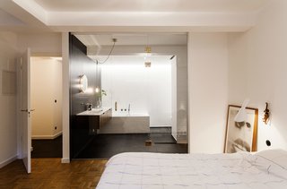 We Can't Get Enough of This German Apartment's Sleek Matte-Black Kitchen - Photo 7 of 11 - In the master bedroom, a Hästens bed is paired with an AJ sconce by Arne Jacobsen for Louis Poulsen. A vintage poster for the 1968 French film Stolen Kisses is a nod to Fabian’s career in advertising, as well as the time period in which the apartment was built.
