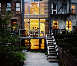 Referencing the motif in the kitchen, wood slats also appear on the rear facade of the home; the variegated cedar planks both modulate light and provide a bit of privacy (above).The garden floor, which accommodates an additional living area and office, also offers access to the backyard.