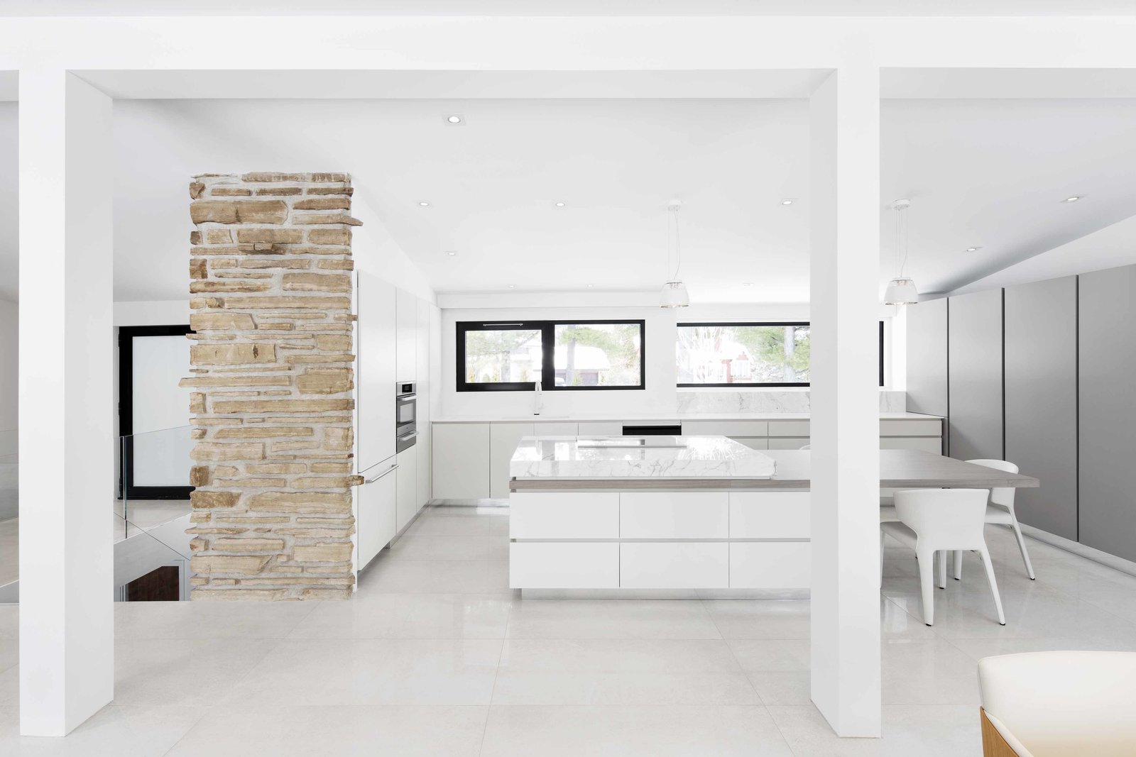 The interior features neutral colors and streamlined appliances like the Miele oven, stovetop, and refrigerator and Espace Cuisine cabinets.