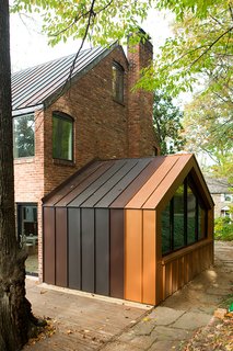 Steel Preserve - Photo 3 of 5 - The den, originally and enclosed porch off the back of the house, was one of the biggest energy-sucking culprits. The designers opened it to the rest of the house to improve circulation, added a pentagonal Weather Shield window, and clad the structure in metal panels matching the roof. 
