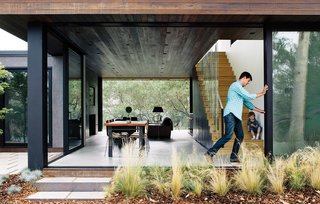 Wouldn't You Like to Have Your Own Private Concerts at Home? - Photo 1 of 10 - With his son, William, watching, architect Noah Walker tries out the floor-to-ceiling Schuco glass doors he integrated into a guesthouse he designed off an existing barn for Nathan Frankel, an amateur violinist, in Beverly Hills, California. The new portion features an open living-dining area.