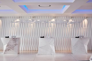 When you proceed to check in, you'll see that Mahmoud had large blocks of solid Thassos marble carved into sharp geometric shapes to contrast against the more classic, softer lines—each one weighs over five tons. The sculpted wall is inspired by the marble draperies of the antique statues of Delos.