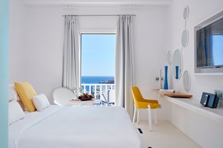 In the Seabreeze Room, marble floors and floating shelves repeat the use of this local material. Custom Flos lighting designs allow the space to softly glow, while a private balcony looks out to the rest of the coastal property.