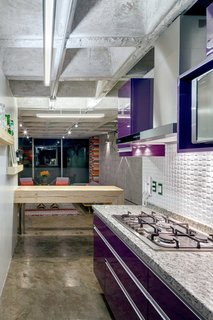 This Retro Apartment Is Finally the Good Kind of Funky - Photo 4 of 7 - Synthetic, organic, and industrial materials coexist in the kitchen. The cabinets are finished in aubergine-purple polyester, the breakfast bench is made of an upcycled timber beam, and the range hood is steel.
