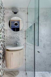 This Retro Apartment Is Finally the Good Kind of Funky - Photo 5 of 7 - Rich Veracruz marble lines one wall of the bathroom, black-and-white tiles of various sizes clad another. 
