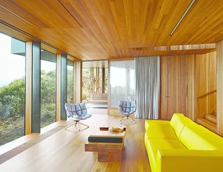 This Surfer Rules the Ocean from a Cliffside House - Photo 3 of 9 - Refusing to fixate on the seascape at the expense of other views, Wardle oriented the living room to a lush grove of trees. A yellow Bend sofa and two Husk chairs, both by Patricia Urquiola for B&B Italia, add splashes of color.