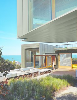 This Surfer Rules the Ocean from a Cliffside House - Photo 8 of 9 - A sliding window between the kitchen and the barbecue area makes outdoor cooking a cinch. "In summer, we eat out there a fair amount," the wife says. Wardle chose zinc for the exterior to complement the trees that surround the house on its northern fringes.