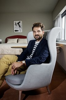 Hayon sits in the Ro armchair he designed for Fritz Hansen, one of the items he placed in the room. "As an artist and a furniture designer, I focus on the small elements rather than the big space," he says. "If you're comfortable on your chair, and it feels good, that's a really good starting point to have a successful space. Then I focus on the rest of the room in terms of color, ambiance, and lighting." 