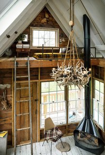The interior of a treehouse at the camp features a wood-burning stove and antler chandelier.