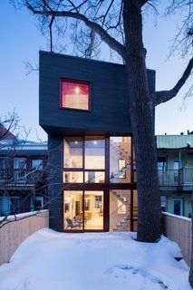 Determined not to destroy the home's limited connection to nature, Microclimat extended the addition only as far as a mature poplar tree in the rear garden. The cantilevered mezzanine is wedged between its trunk and boughs. 