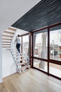 The expansion creates a narrow intermediary space between the yard and existing home. This sliver contains a light steel staircase and two new sun rooms for reading.
