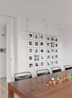 Bauhaus by the Sea - Photo 5 of 8 - In the dining room, Mies van der Rohe chairs surround a custom-made cherry table. Black-and-white photographs of Sasseen's children and grandchildren are arranged systematically on the back wall.