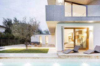 A lap pool and protected courtyard with a lone tree flank the home. 