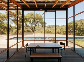 In line with the family’s active lifestyle, the kitchen is also situated outside; to the south of it, a screened-in area of the porch, clad in ipe and black fiberglass mesh, serves as the impromptu dining area. The table and chairs are from Black’s Farmwood, and the ceiling fan is by Fanimation. 