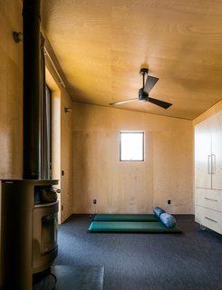 The family keeps the plywood-lined interiors sparse, using campaign furniture and sleeping bags when they stay here; the floor coverings are by Chilewich, and the wood-burning stove is by Rais. 