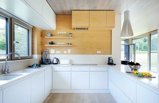 The Home That Arrived by Crane - Photo 3 of 3 - Bright interior finishes, including whitened oak on the floor and ceiling and Kitchen Collection’s Malmo cabinets in porcelain and oak colorways, were installed off-site. 