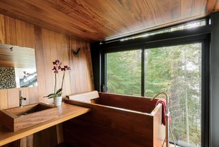 The Japanese-style bathroom, which is clad in teak, features a matching tub and sink by Bath in Wood.