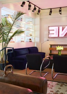 This Boutique Hotel Loves its City Like No Other - Photo 4 of 14 - A comfortable seating area is situated a couple of steps into the hotel. The navy-blue sofa is ASH's design and the vintage armchairs with chrome handles are by Jindrich Halabala. Iron Origami fabricated the square coffee table just past the chairs. Artist Oliver Clegg created the neon sign.