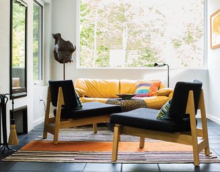 A Lakeside Home Brings a Scandinavian Sensibility to the Midwest - Photo 5 of 6 - One end of the gathering hall is furnished with a pair of lounge chairs and an iron side table, all from CB2 and since discontinued. Brogan designed the rug and had it made at the Mehmet Çetinkaya Gallery in Istanbul. Brogan says she chose the Maralunga sofa by Vico Magistretti for Cassina "for the color and the scale in a small area near the tiny fireplace."
