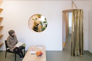 A Quirky Renovation Brings an Indoor Garden to the Center of Madrid - Photo 3 of 6 - A cutout oculus in the living room offers a peek into the plant-filled bath, while a curtain can be drawn to control airflow.