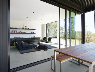 When Prefab Is Painless - Photo 3 of 7 - Located just off the kitchen, this room was originally designed for dining—the adjustable Ligne Roset Crescendo coffee table can be raised to 28.75 inches—but most days Bill and Abbie prefer to eat outside or at their casual Caesarstone-topped kitchen island. Today the space serves as a sunny reading spot and guest room, with a convertible futon (from Ligne Roset, since discontinued) and a set of leather-and-steel Paulistano armchairs from Design Within Reach.