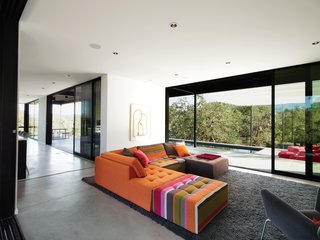 When Prefab Is Painless - Photo 4 of 7 - The Mikado 2 sofa by Hans Hopfer for Roche Bobois is a bright and cheery centerpiece in the otherwise sedate living room. The nubby wool Photon rug from Design Within Reach warms up the expanse of concrete. The framed drawing is by the Los Angeles–based artist Daniel Brice. Huge sliding doors open the house to the outdoors and virtually double the Burtons' living space.
