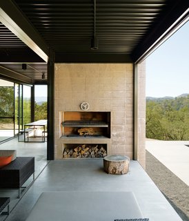 When Prefab Is Painless - Photo 5 of 7 - Passionate cooks, the Burtons installed a Mugnaini wood-fired oven in their kitchen and had a custom Grillery fireplace-barbecue built into the concrete block wall on their deck. Beneath the grill they store oak firewood collected from their property.