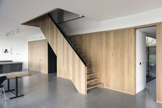 Bold House Doubles as a British Town's Welcome Sign - Photo 3 of 6 - A palette of natural materials is employed in both the interior and exterior. An oak wall and staircase, designed by Jeremy Pitts, join a floor made of gray terrazzo tile. 