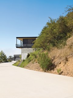 This High-Flying Home Tackles a Sharp Slope - Photo 1 of 8 - To deal with a Malibu site’s sharp incline, architect Bruce Bolander set the steel, concrete, and glass house on caissons. A deep wraparound porch nearly doubles the home’s living space and offers the ideal perch for outdoor dining and taking in spectacular views of the surrounding canyon. The garage serves as resident Dave Keffer’s home office.