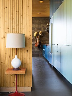 This High-Flying Home Tackles a Sharp Slope - Photo 2 of 8 - A colorful, laminate-clad wall of storage stretches seamlessly from the kitchen—where it holds a full-size built-in Sub-Zero refrigerator and freezer, a Miele dishwasher, a Bosch cooktop, and a tiny convection oven—to the bedroom, where it contains the couple’s clothing, shoes, and linens.