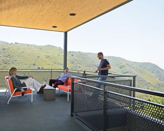 This High-Flying Home Tackles a Sharp Slope - Photo 5 of 8 - Wright and Keffer (standing) hang out on their deck with Bolander, who lives just across the road. The chairs, designed by Bolander, are upholstered in Sunbrella fabric.