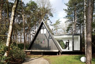 This Minimal Addition Looks Magical in the Belgian Forest - Photo 1 of 4 - Adding 290 square feet to this already small (just 566 square feet) black A-frame in Brecht, Belgium, was all the local building ordinances allowed, but the architects at dmvA found that a single wing extended out to the side gave resident Rini van Beek all the storage and living space that she needs.
