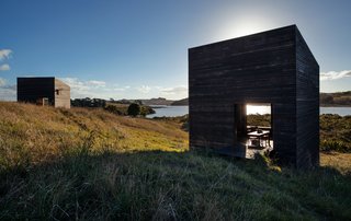 Before building on the North Island of New Zealand, two friends spent years replanting the site. The 290-square-foot structures Cheshire Architects designed for them reject the local trend of oversize beach houses—instead, they sit on the landscape like a pair of minimalist sculptures.