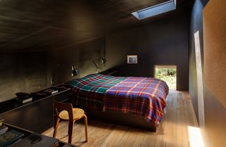 The formply used to line the black interior creates a "small, inky bubble of space," Cheshire says. "It’s incredibly calm and quiet as a consequence." His firm designed the built-in bed and cabinetry. The two Type 75 lamps are by Kenneth Grange for Anglepoise, and the Chair 65 is by Alvar Aalto.