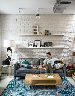 Living Area: Bischoff’s team retained the exposed brick on the interior, painting much of it white to help the space reflect sunlight. "There was an interest in having an open, more contemporary layout, but we still wanted some sense of living in this building that’s 100 years old," Bischoff says. "That motivated us a lot to keep the brick. It’s a very subtle echo of what the house originally was." Enclosing the ductwork would have forced the architects to lower the ceiling or install a subpar air-conditioning system. So it was left exposed, contributing to the floor’s loftlike atmosphere. New meets old with the furnishings as well: An antique barbershop pendant provides contrast to a sculptural lamp and a rug from Anthropologie. Investment buys were made with budget in mind, like the leather sofa scored at ABC Carpet & Home’s outlet store.